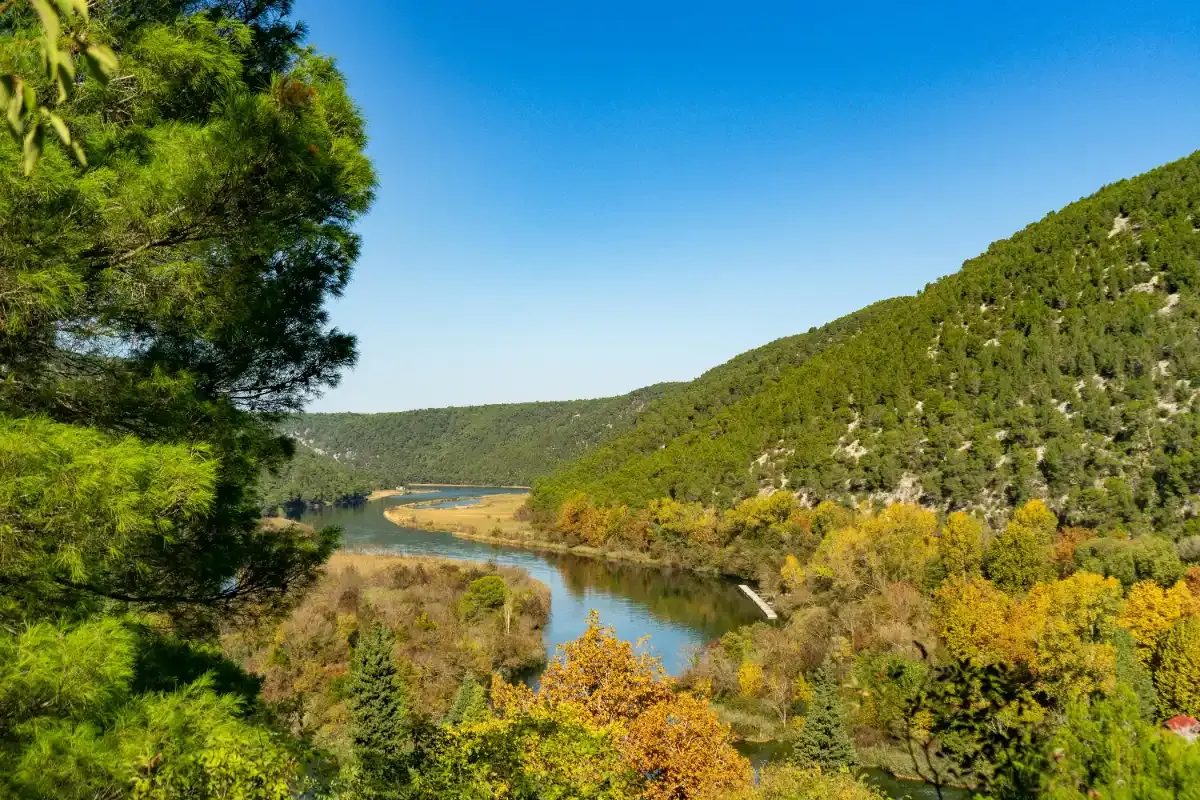 Barco de excursión navegando por el río Krka entre cañones y vegetación mediterránea