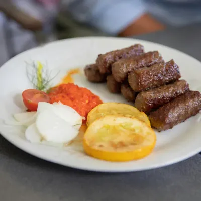 Ćevapi servidos en pan lepinja con cebolla y ajvar, comida rápida típica de Croacia
