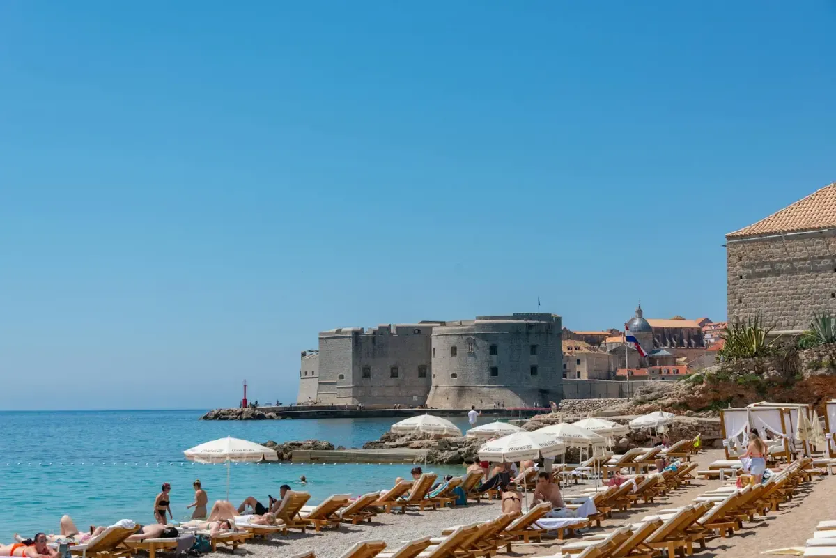 Playa de Banje en Dubrovnik con aguas cristalinas del Adriático y vista a las murallas